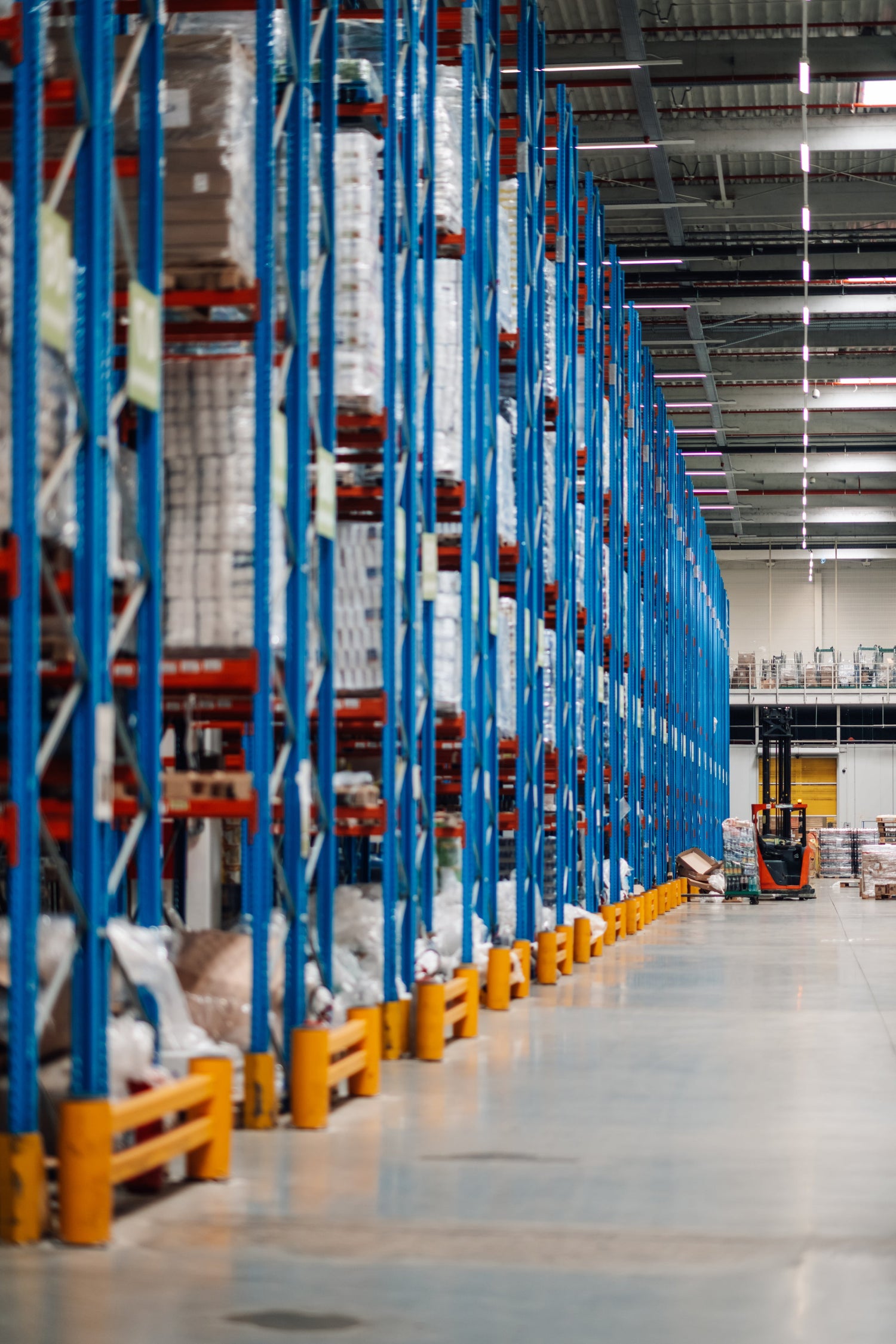 High-rack storage system in a warehouse with blue metal shelves and orange safety blocks.